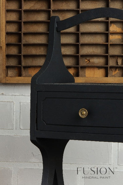 Fusion Mineral Paint | Table painted in coal black in front of a white brick wall.