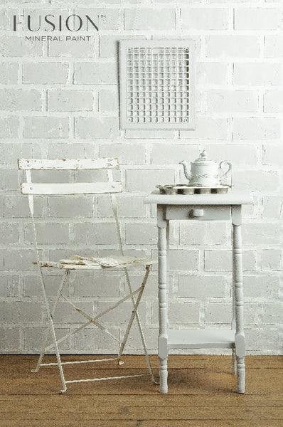 Fusion Mineral Paint | Off white table and chair setup with decor  in front of a white bring wall on wood flooring.