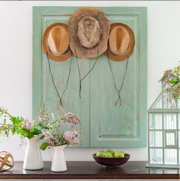 Crackled green cupboard with hats hanging.