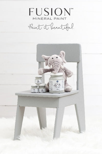 Fusion Mineral Paint | Chair painted with little lamb painting with decor against a white wall with white fuzz on the floor.
