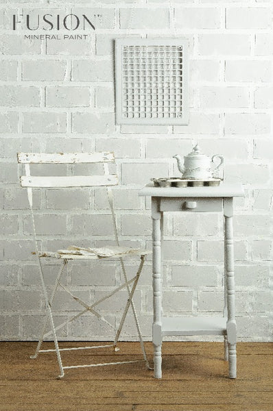 Fusion Mineral Paint | Off white table and chair setup with decor  in front of a white bring wall on wood flooring. 