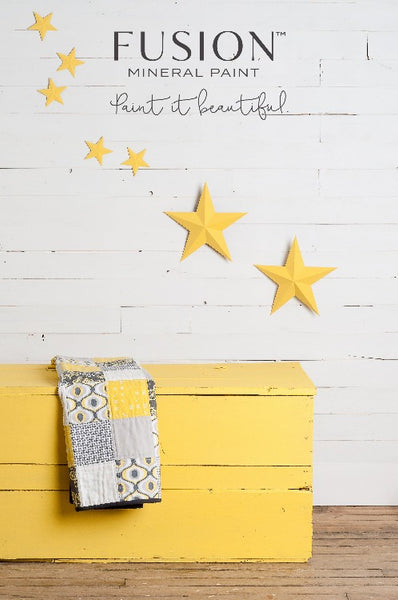 Fusion Mineral Paint | Wooden chest painted in Little Star in front of a white wall with yellow stars hanging on it.