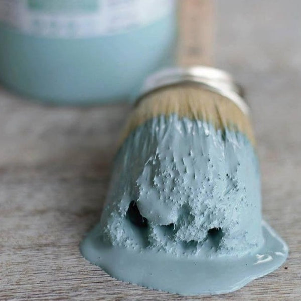 Fusion Mineral Paint | Round paint brush dipped in heirloom dripping on floor with paint jar in background.
